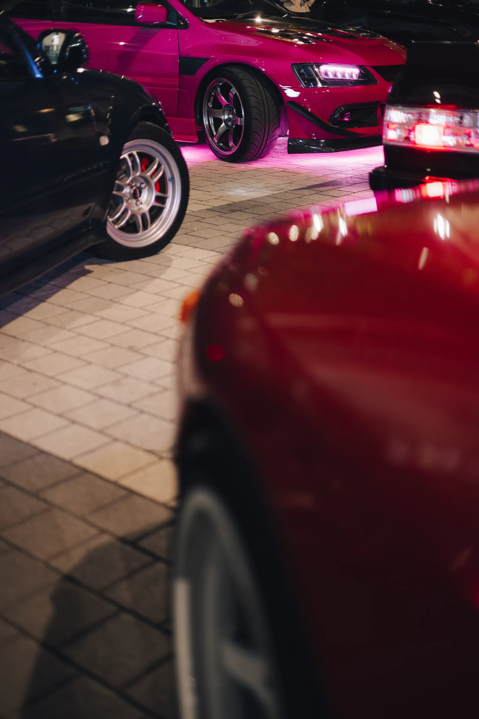 Magenta Evo under pink underglow, lined up with the other builds on the cobbles