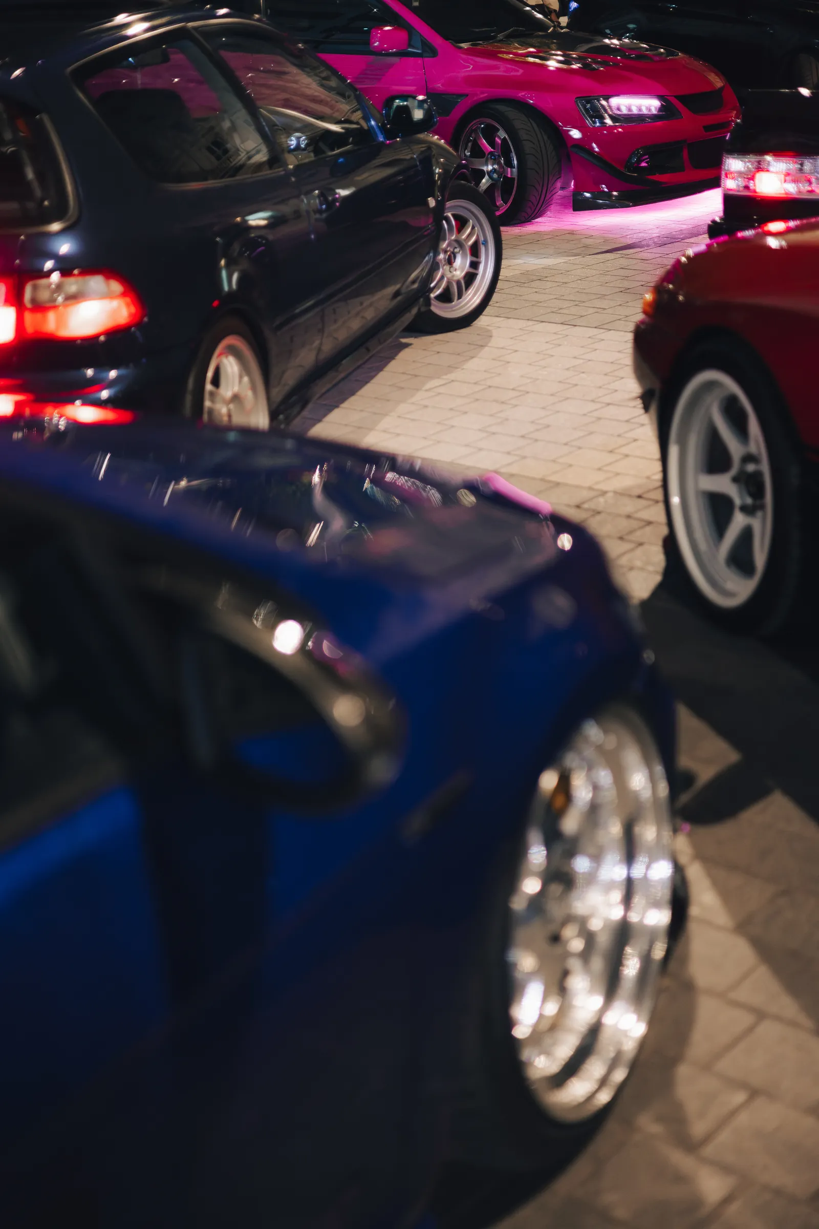 Blue Civic, black Civic and a magenta Evo lined up on the cobbles at night