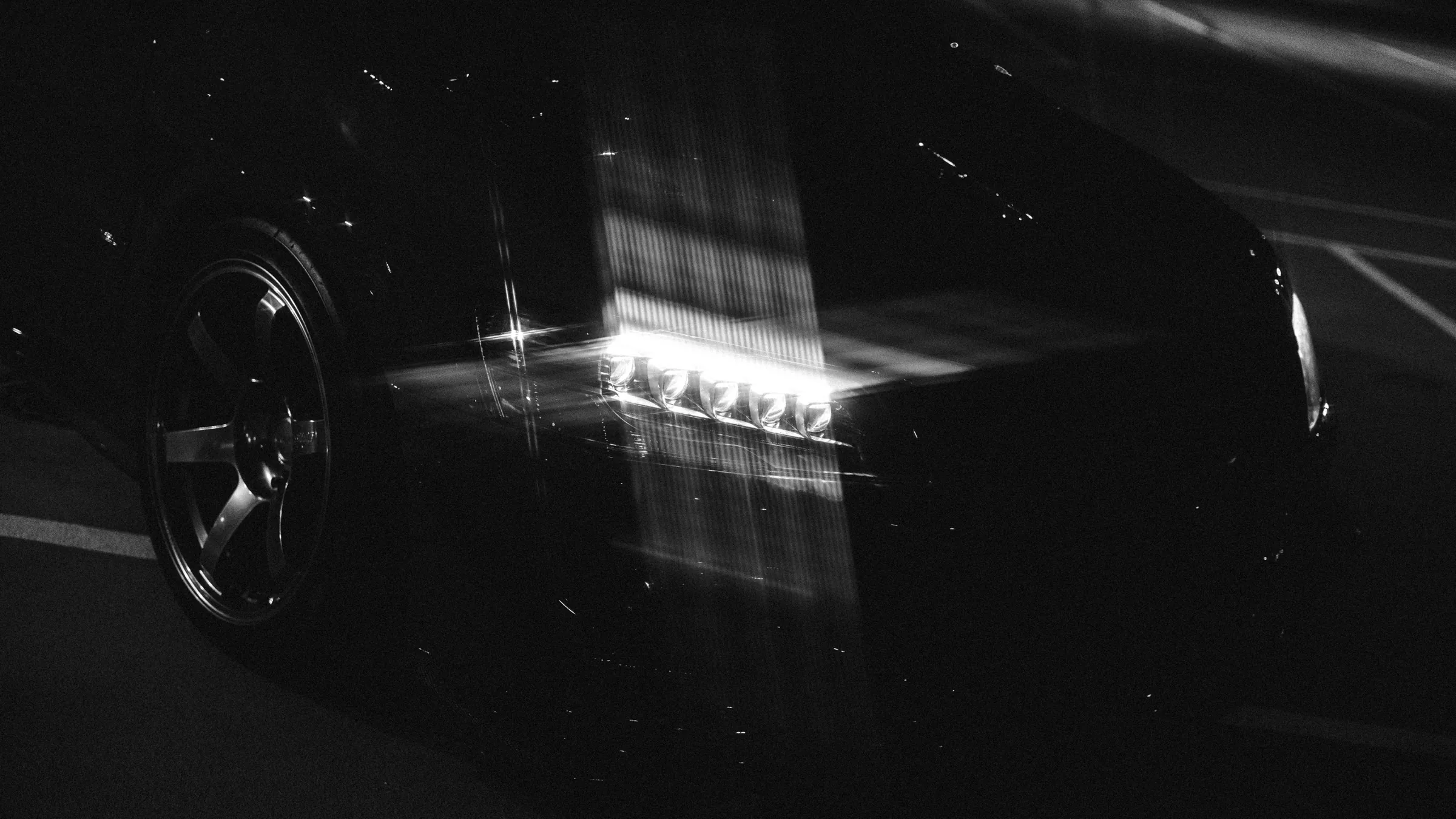 Mitsubishi Lancer Evolution headlight and wheel, black and white long-exposure light trails