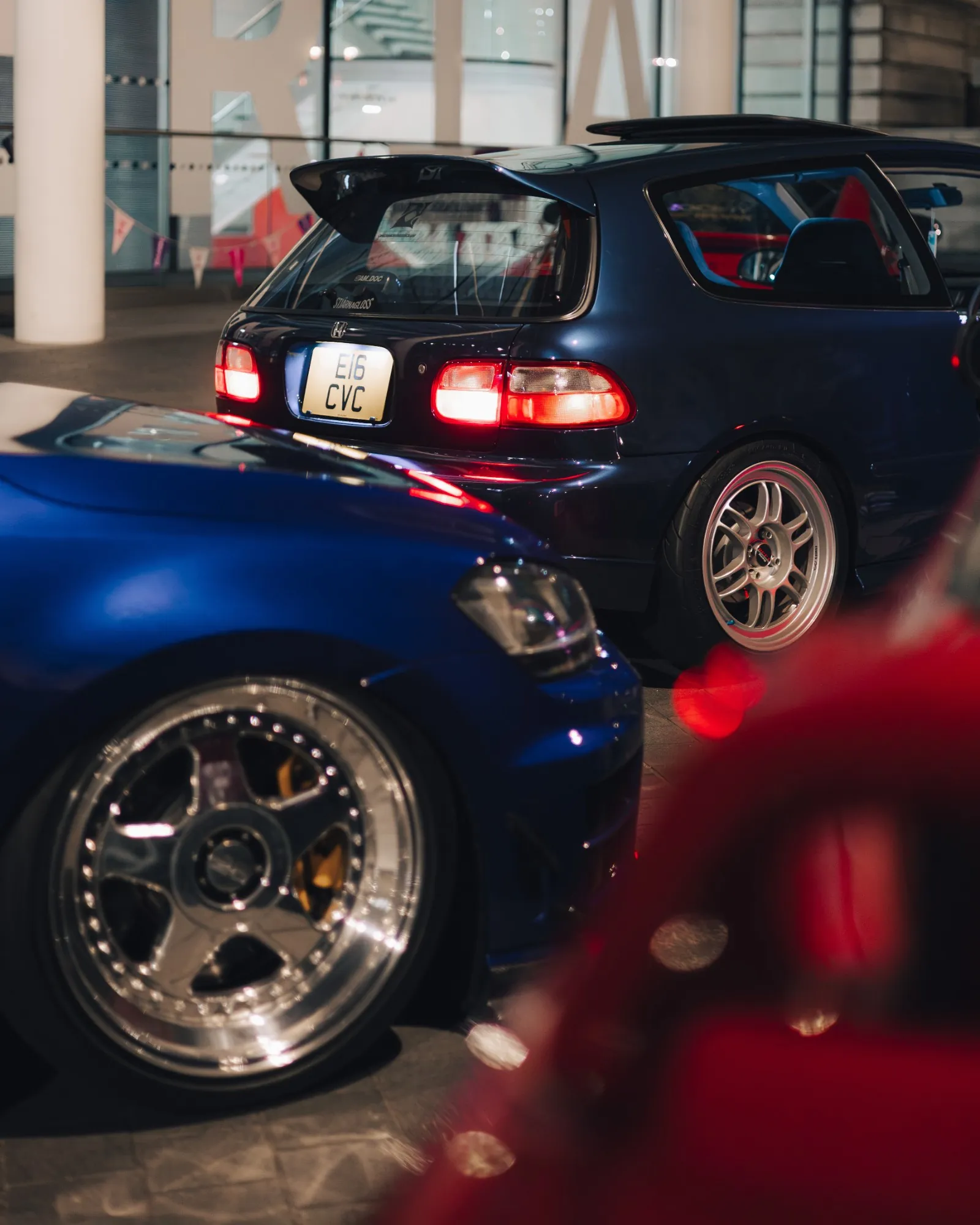 Magenta Evo IX beside a black Civic on polished wheels