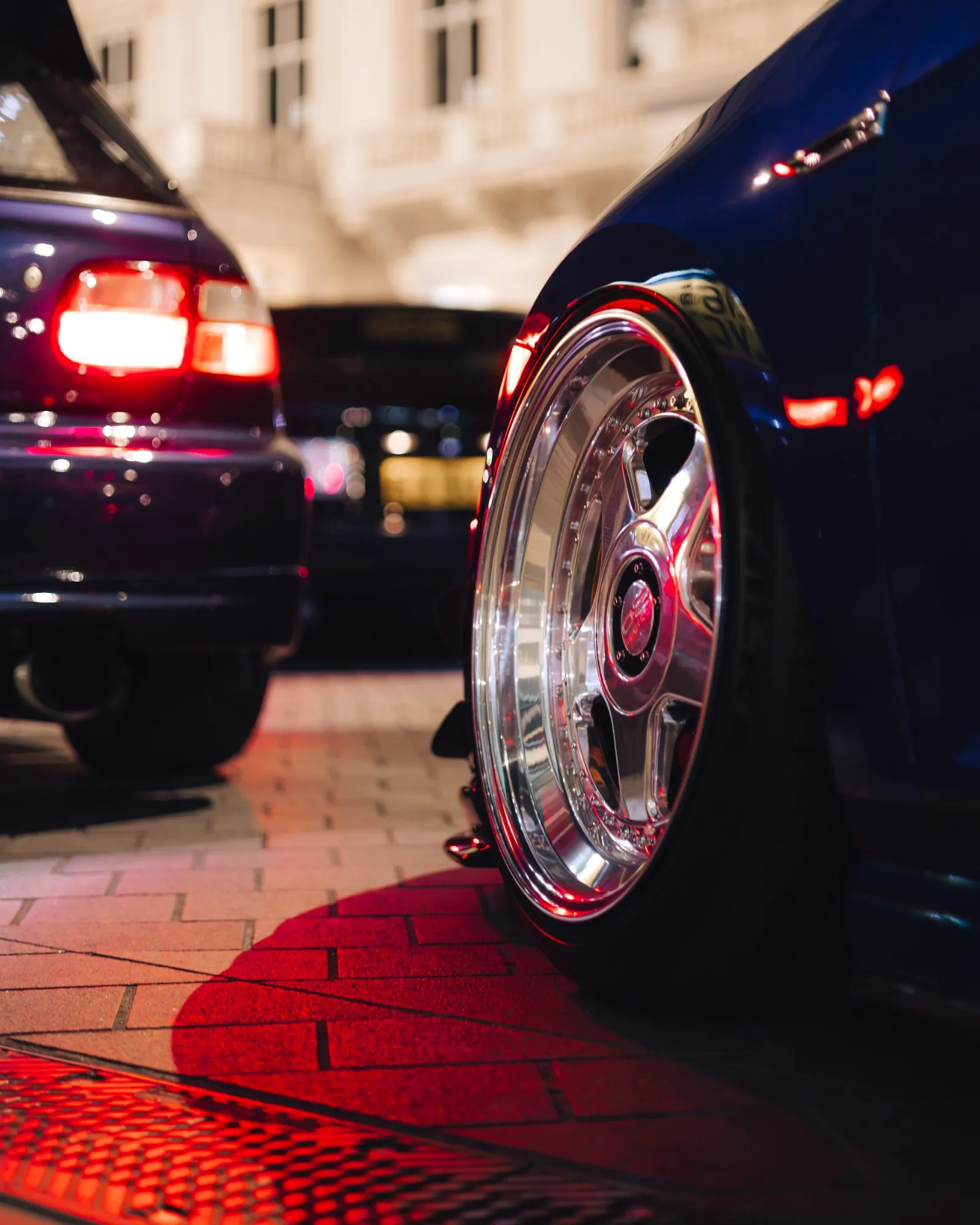 Polished OZ Racing wheel with Civic tail lights behind, red light on the cobbles